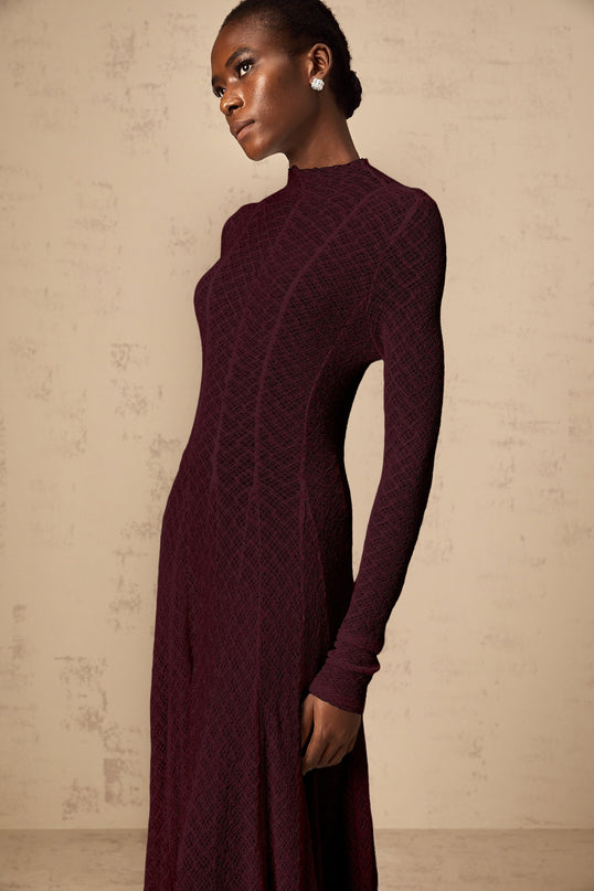 Woman wearing long red lace maxi dress with wavy pattern and flowing skirt