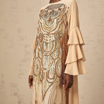 Woman wearing long sequined tulle dress with ruffle sleeves and flowing maxi skirt in elegant pose