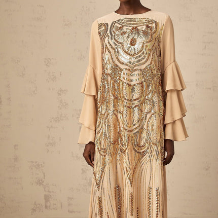 Woman wearing long shimmering tulle dress with ruffled sleeves and sequin details