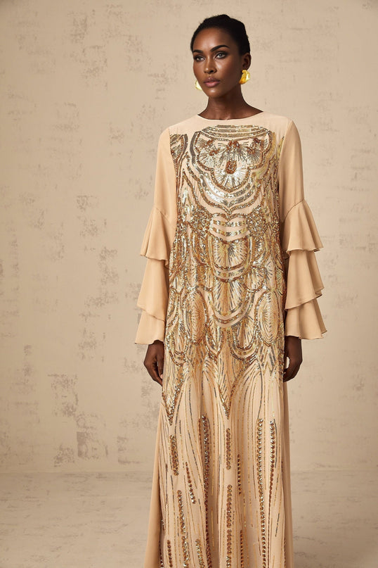 Woman wearing long shimmering tulle dress with ruffled sleeves and sequin details