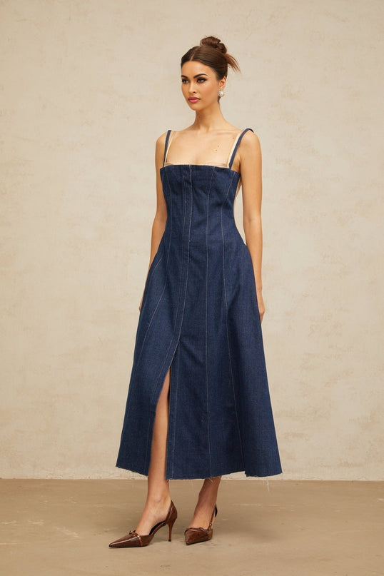 Woman wearing long sleeve indigo blue denim dress with panelled design reaching mid calf length