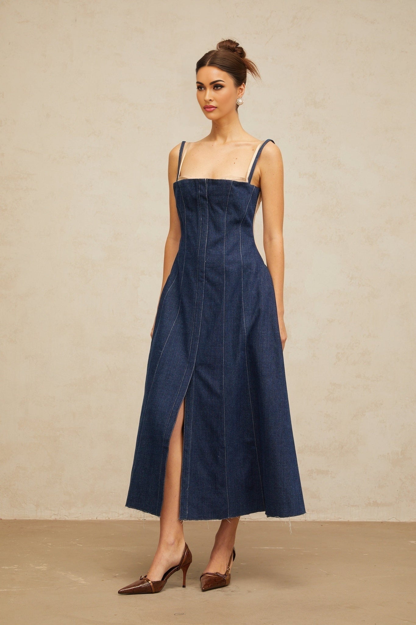 Woman wearing long sleeve indigo blue denim dress with panelled design reaching mid calf length