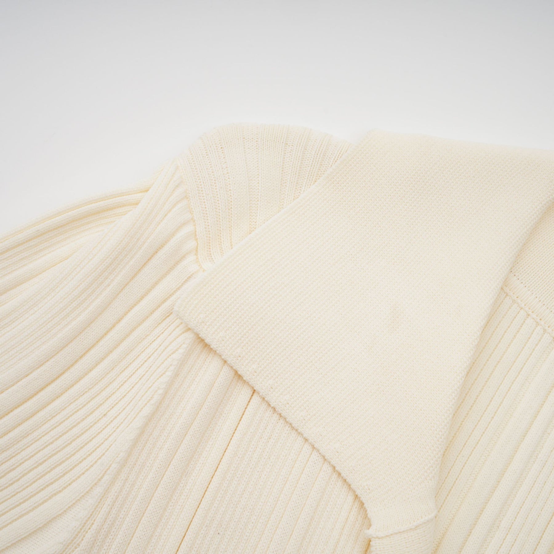 Woman wearing long sleeve ribbed knit midi dress in neutral color standing against plain background