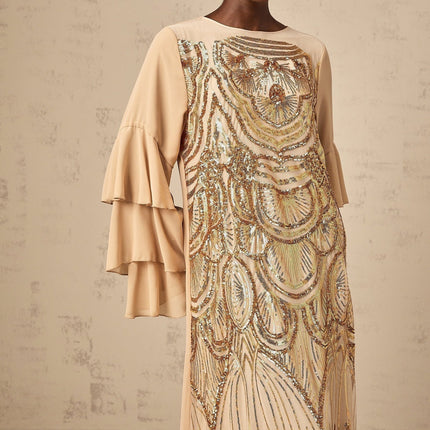 Woman wearing long sparkly tulle dress with ruffled sleeves and sequin details