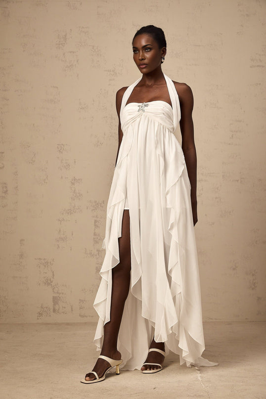 Woman wearing long white chiffon maxi dress with ruffled halter neck