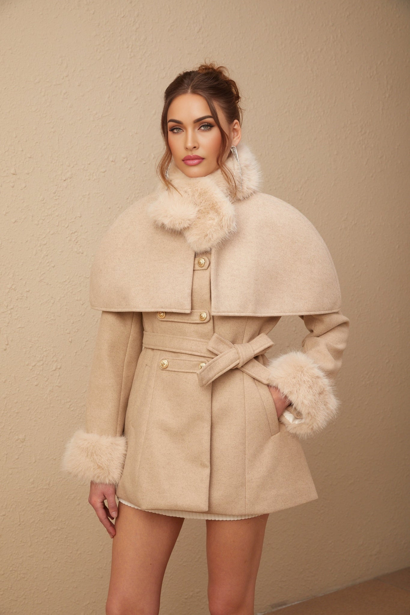 Woman wearing long white faux fur coat with detachable cape collar