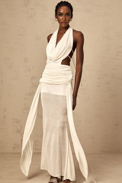 Woman wearing long white halterneck maxi dress with open back standing in sunlit outdoor setting