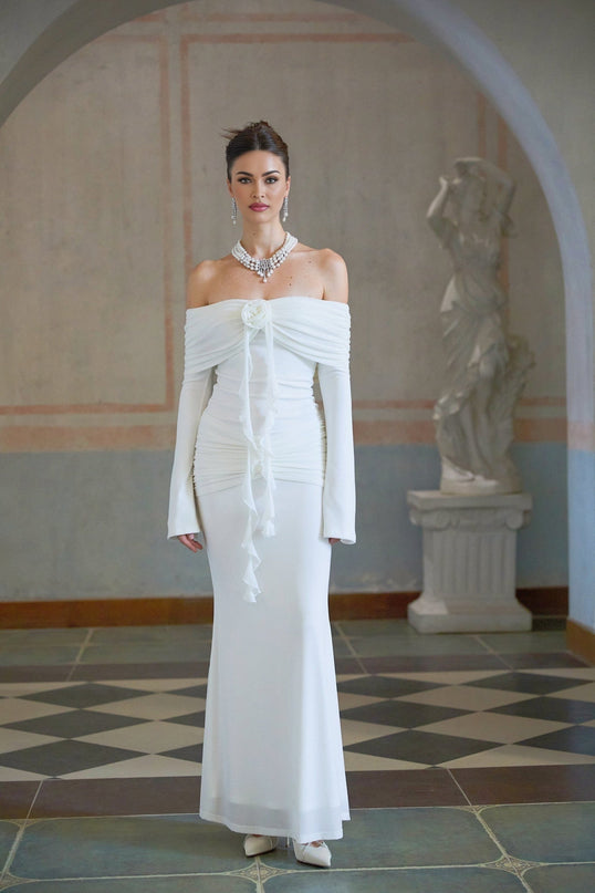 Woman wearing long white knit dress with glittery floral appliques standing in elegant pose