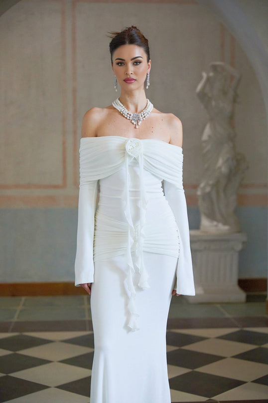 Woman wearing long white knit dress with glittery floral appliques standing in relaxed pose