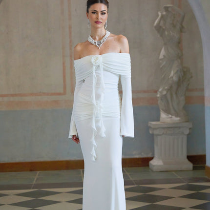 Woman wearing long white knit maxi dress with glittery floral appliques standing in neutral background