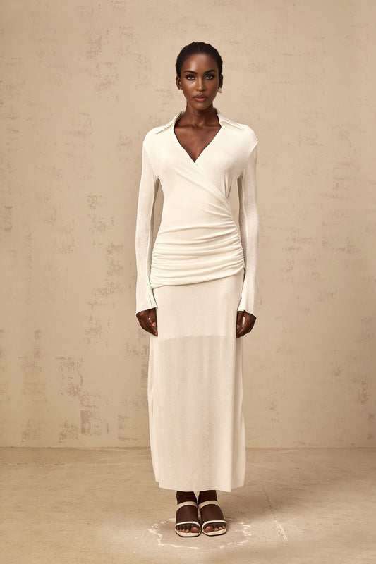 Woman wearing long white knit maxi dress with ruched details and fitted silhouette