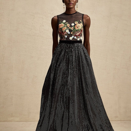 Woman wearing long white maxi dress with colorful floral embroidery embellishments