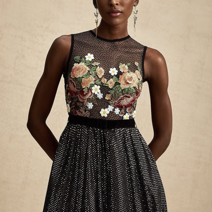 Woman wearing long white maxi dress with colorful floral embroidery embellishments