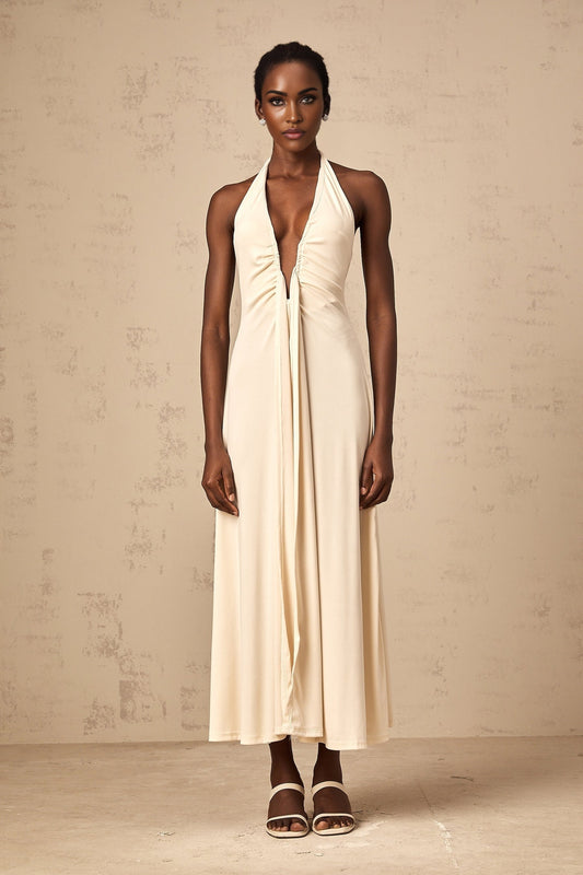 Woman wearing long white maxi dress with deep V neckline and draped design