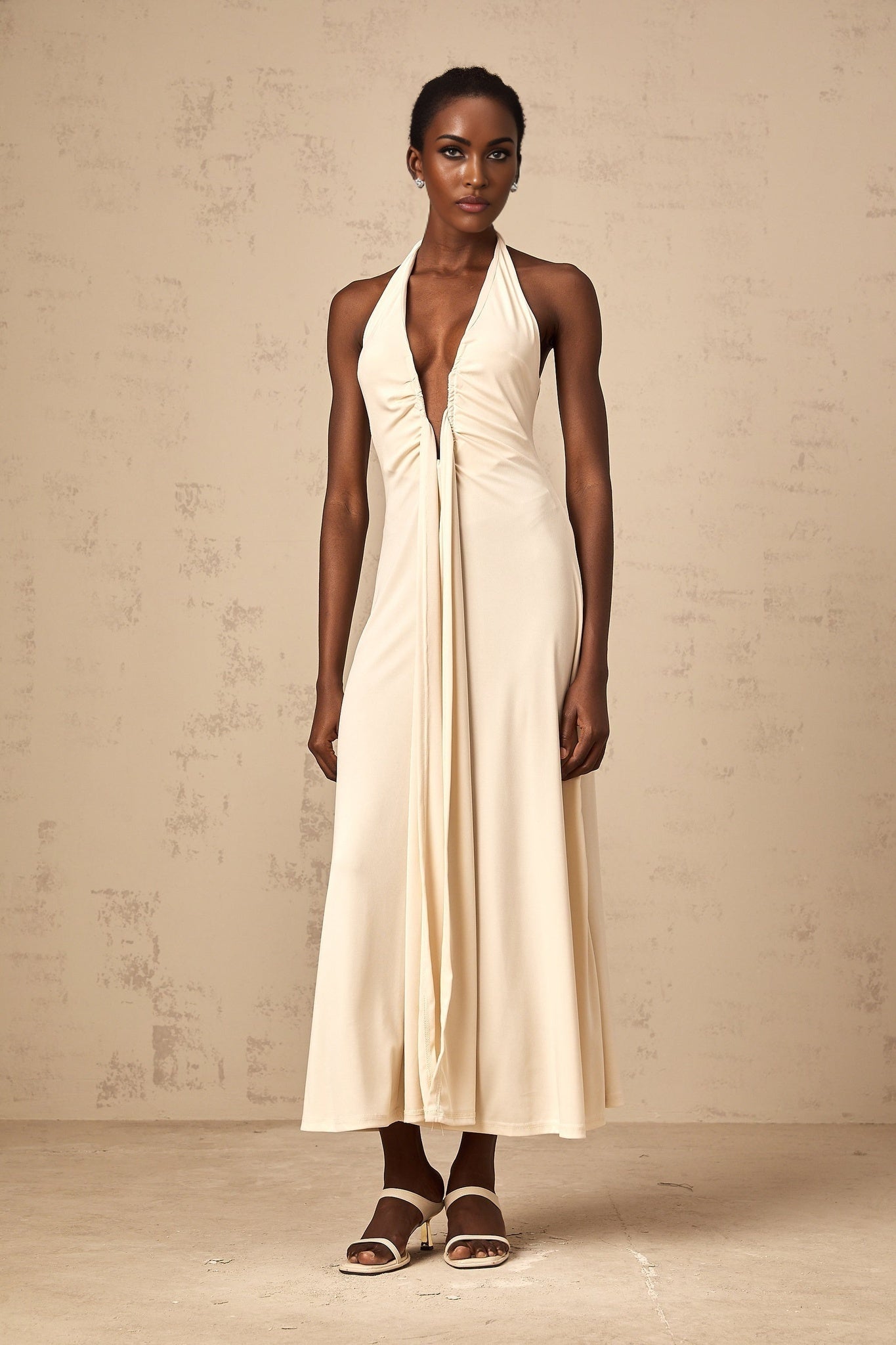Woman wearing long white maxi dress with deep V neckline and draped details