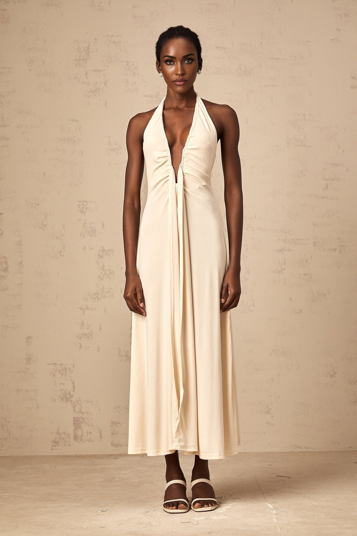 Woman wearing long white maxi dress with deep V neckline and draped fabric detail