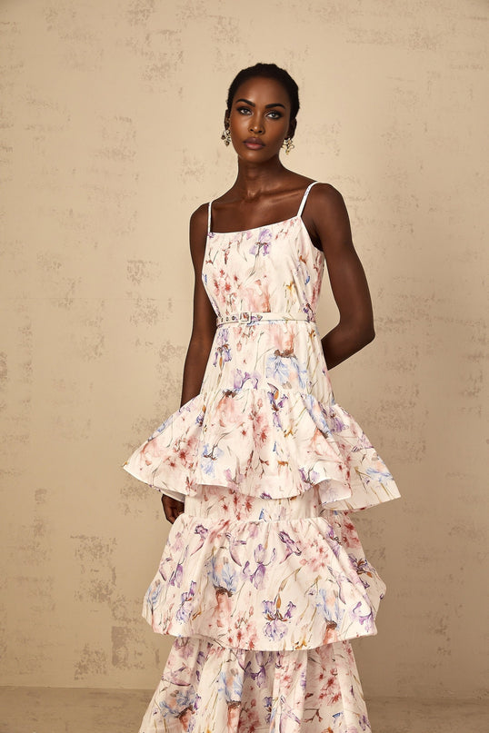 Woman wearing long white maxi dress with floral print and tiered ruffles