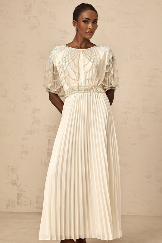 Woman wearing long white pleated maxi dress with crystal embellishments