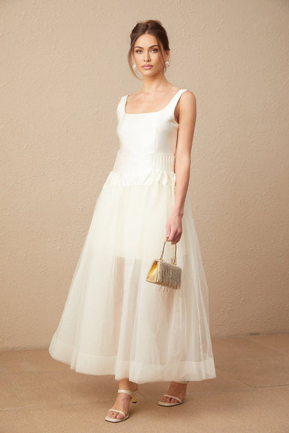 Woman wearing long white satin dress with tulle panels and flowing maxi skirt