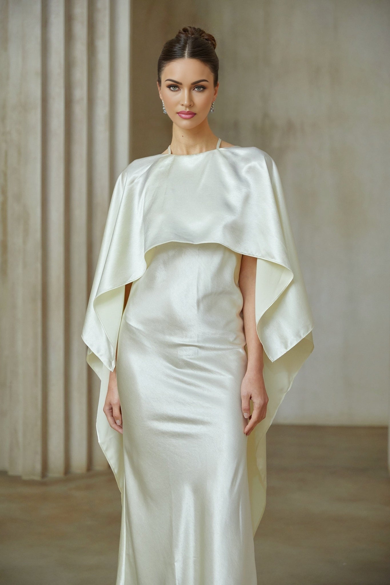Woman wearing long white satin maxi dress with shawl panel detail flowing fabric elegant silhouette