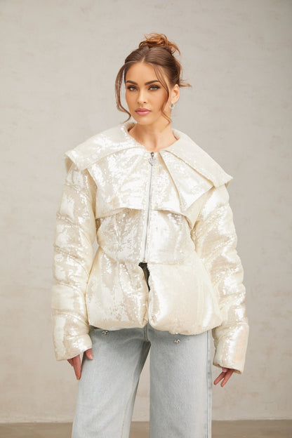 Woman wearing long white winter coat with shiny sequin embellishments and puffy down insulation