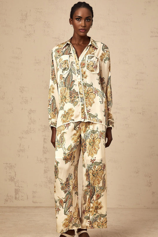 Woman wearing matching beige floral print shirt and trousers set with loose fit and neutral tones