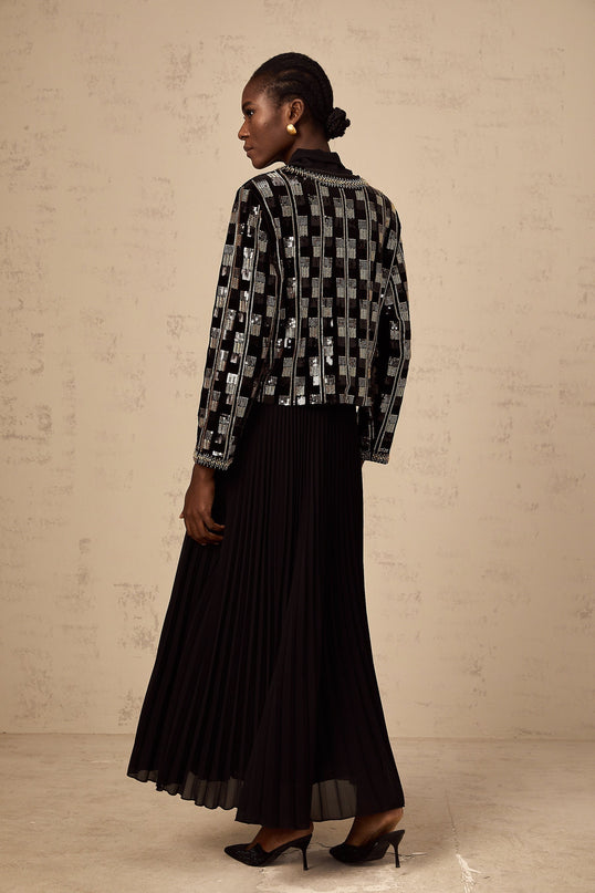 Woman wearing matching black sequined cardigan and dress set Cardigan has long sleeves and open front Dress is sleeveless with knee length skirt