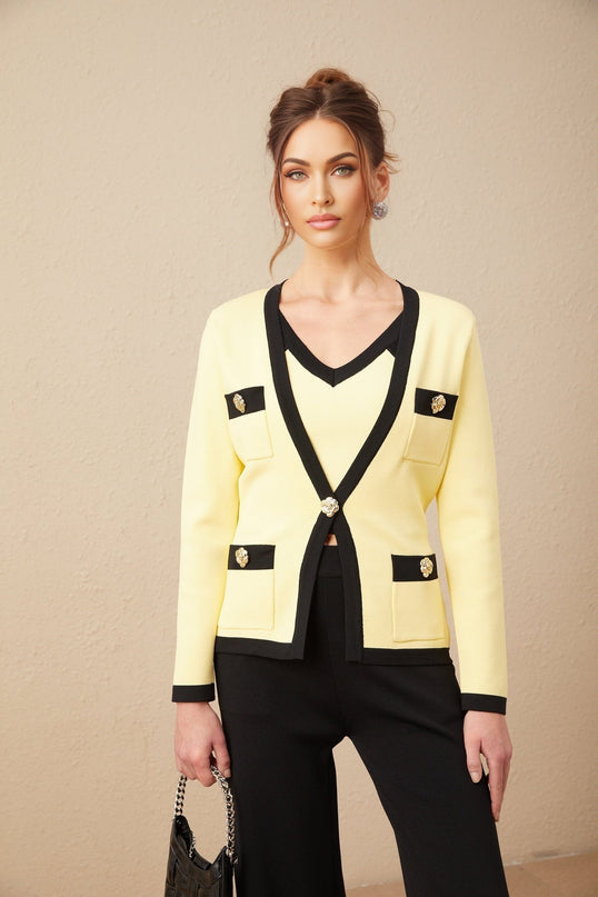 Woman wearing matching knit cardigan vest and trousers set in light color with contrasting dark trim