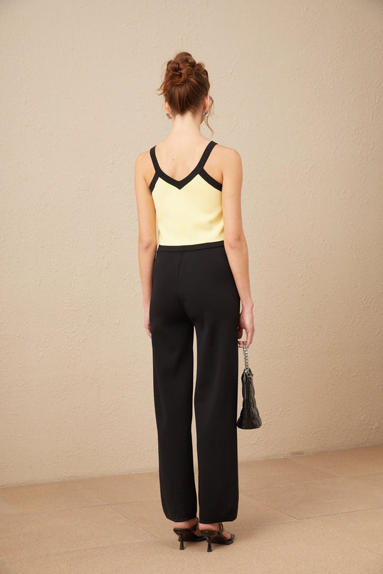 Woman wearing matching knit cardigan vest and trousers set with contrasting trim in Eloise style