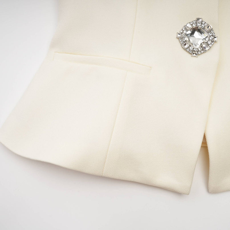 Woman wearing matching white jacket and shorts set adorned with crystal embellishments