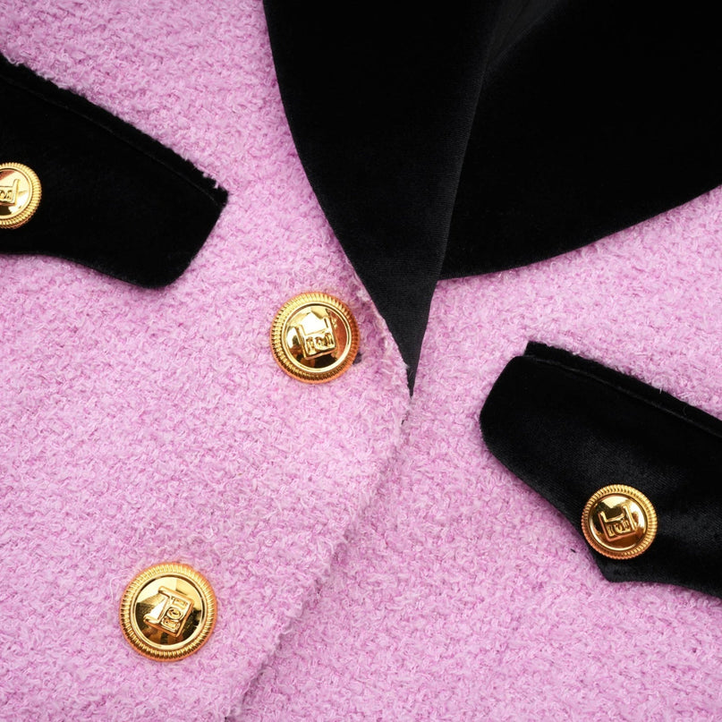 Woman wearing navy blue blazer and matching skirt set standing in front of plain background