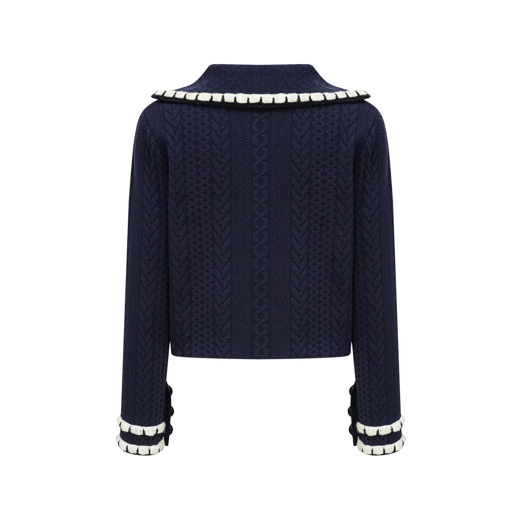 Woman wearing navy blue crochet knit cardigan and matching trousers standing against plain background