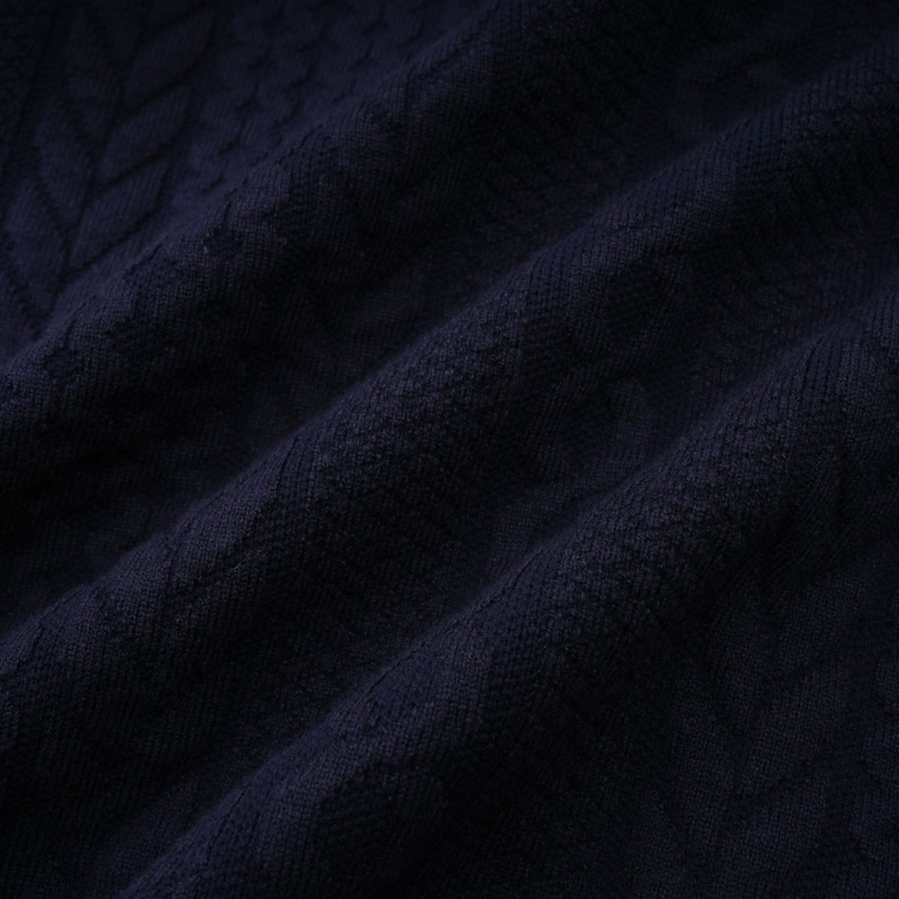 Woman wearing navy blue crochet knit cardigan and matching trousers standing against plain background