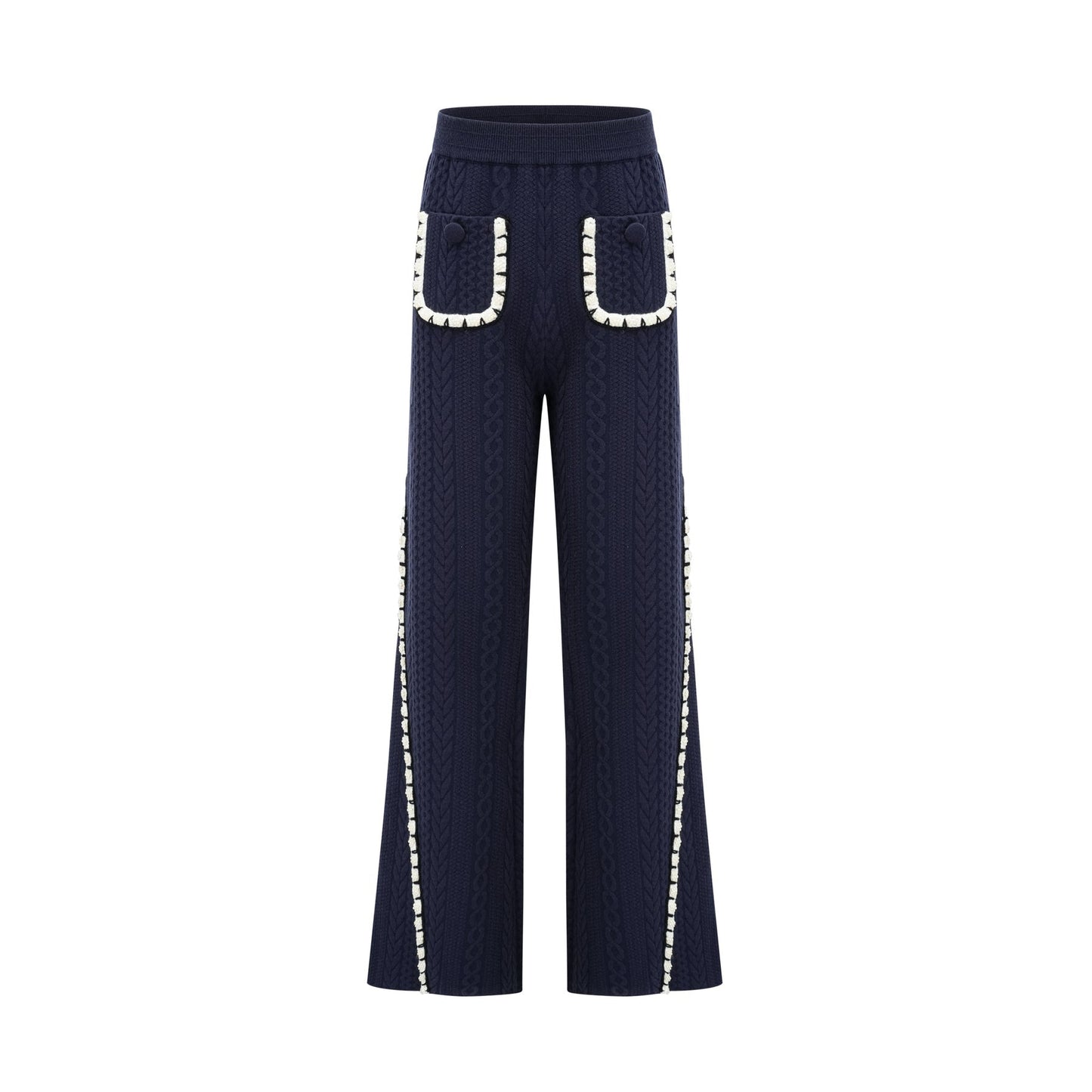 Woman wearing navy blue crochet knit cardigan and matching trousers standing against plain background