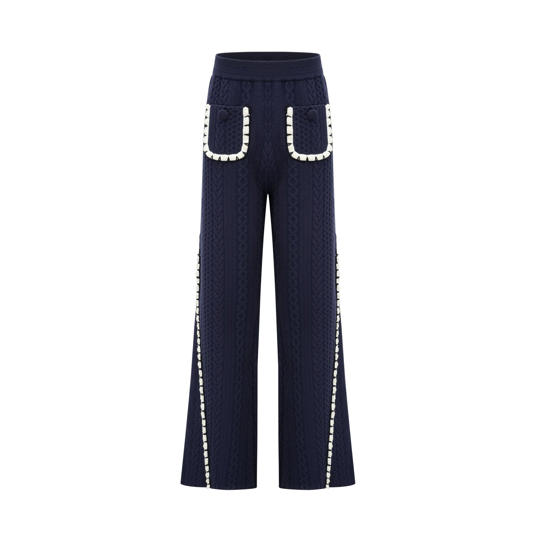 Woman wearing navy blue crochet knit cardigan and matching trousers standing against plain background