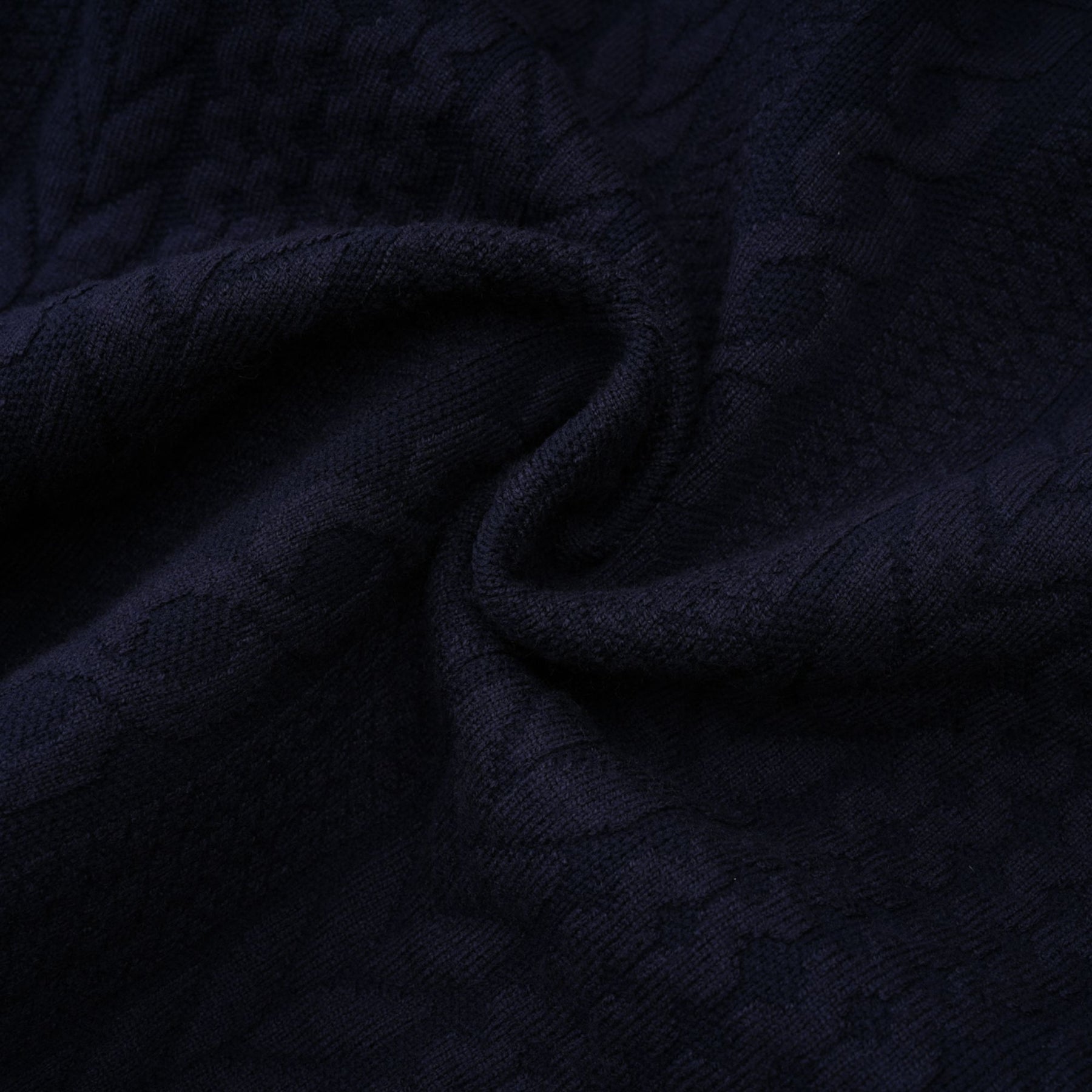 Woman wearing navy blue crochet knit cardigan and matching trousers standing against plain background