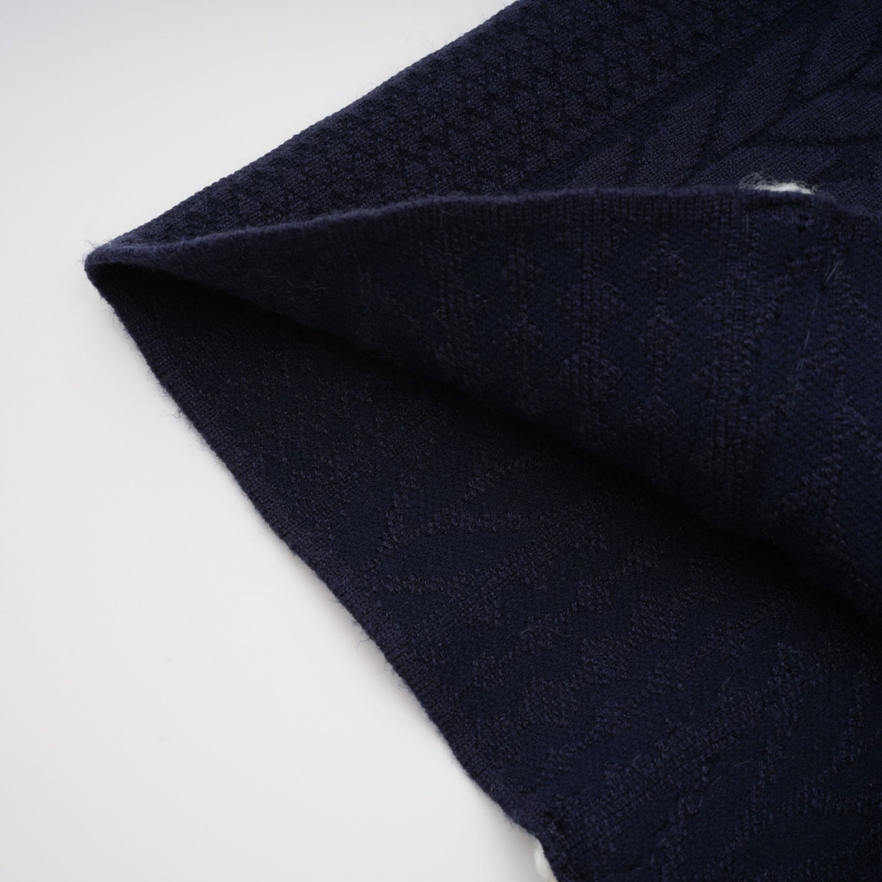 Woman wearing navy blue crochet knit cardigan and matching trousers standing against plain background