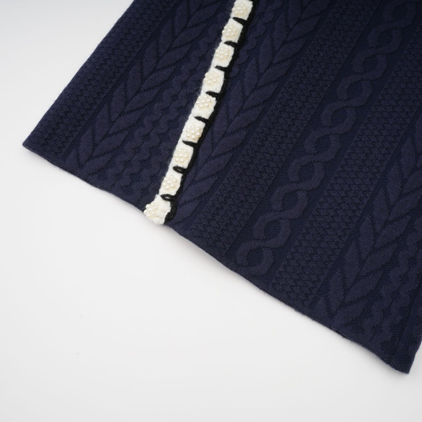 Woman wearing navy blue crochet knit cardigan and matching trousers standing against plain background
