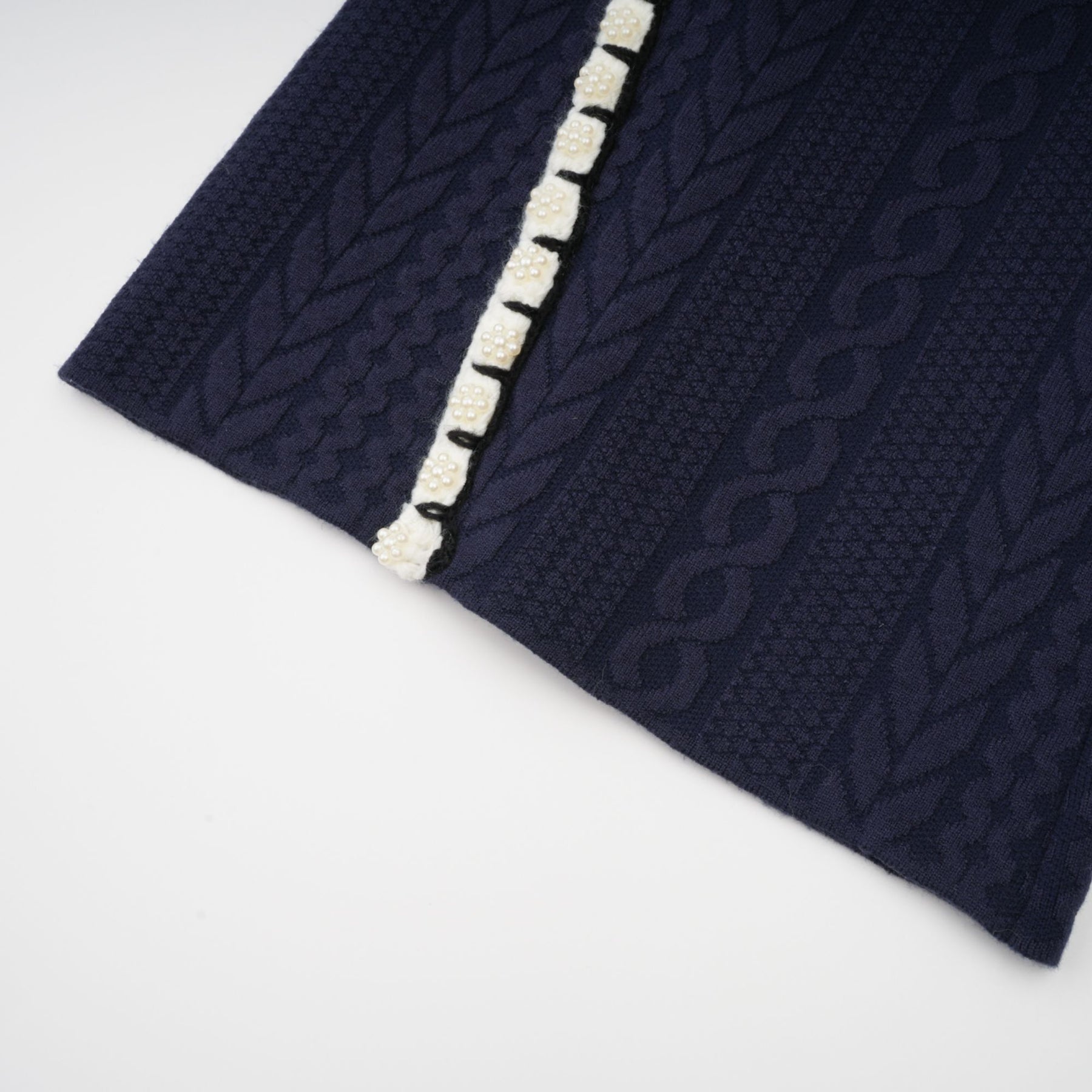 Woman wearing navy blue crochet knit cardigan and matching trousers standing against plain background