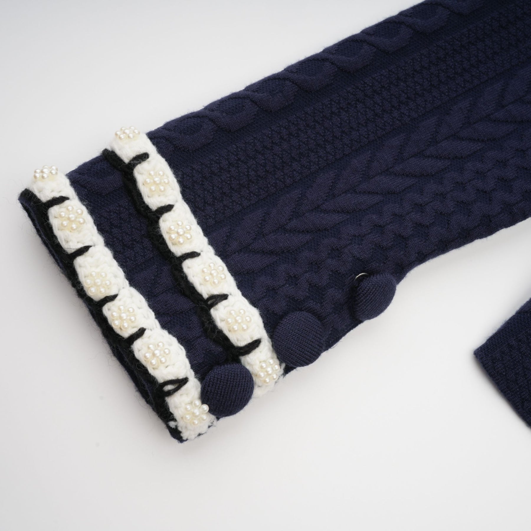 Woman wearing navy blue crochet knit cardigan and matching trousers standing in relaxed pose