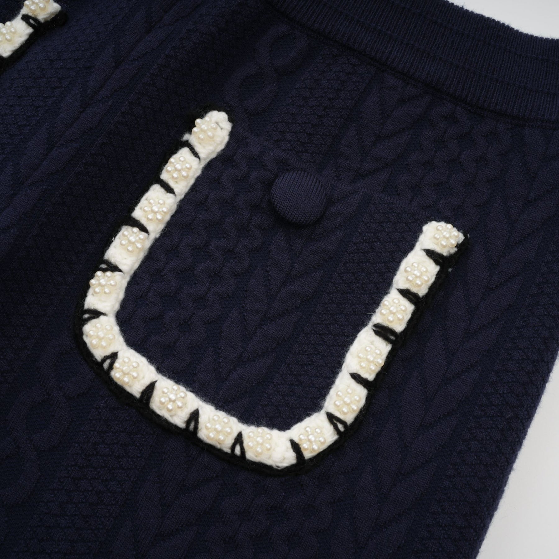Woman wearing navy blue crochet knit cardigan and matching trousers standing in relaxed pose