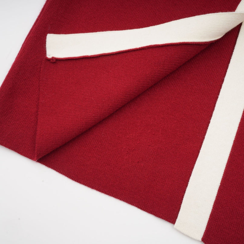 Woman wearing navy blue offshoulder knit midi dress with long sleeves standing against plain background