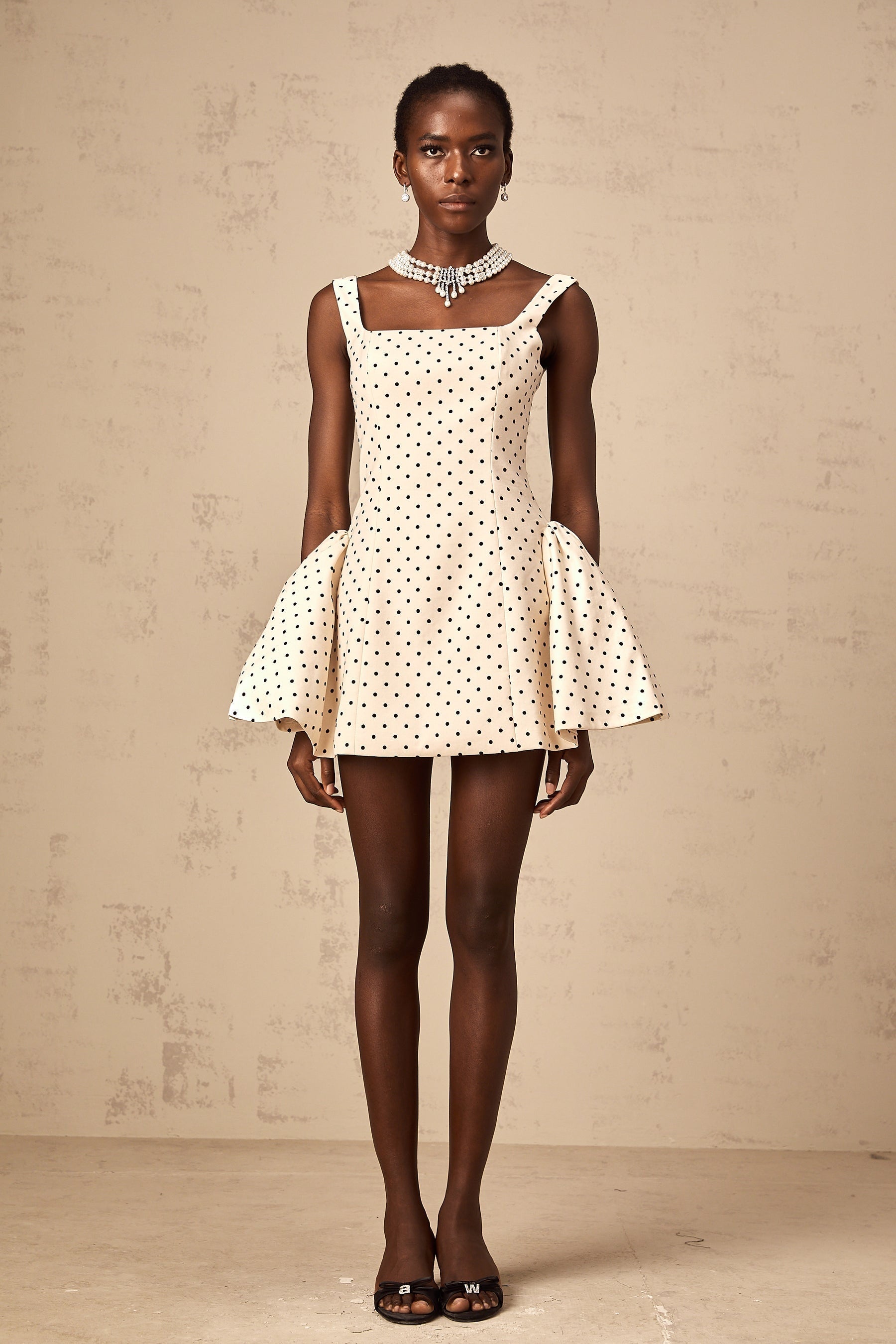 Woman wearing neutral colored mini dress with polka dot pattern and puff sleeves