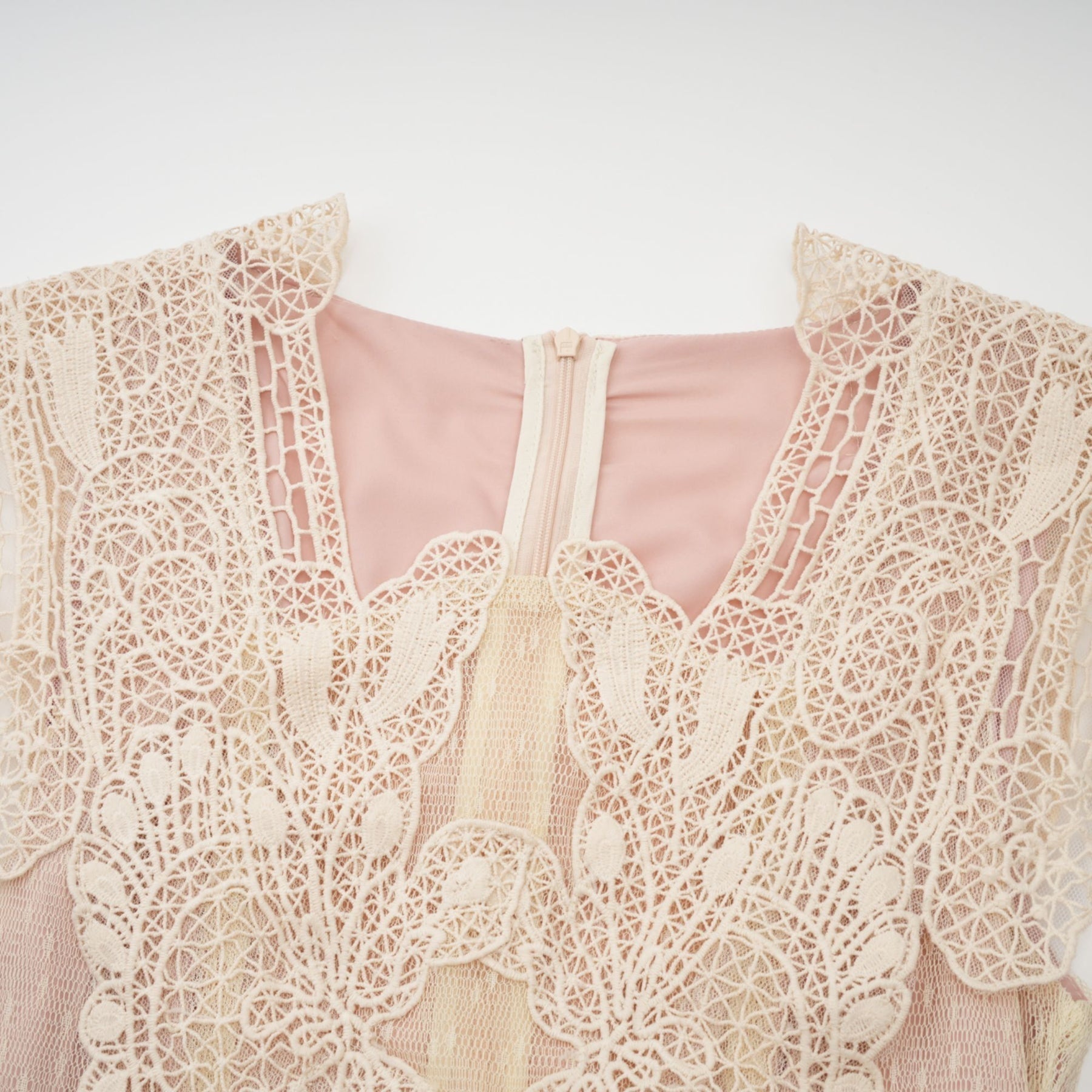 Woman wearing neutral colored tulle midi dress with floral lace panelling and sleeveless design