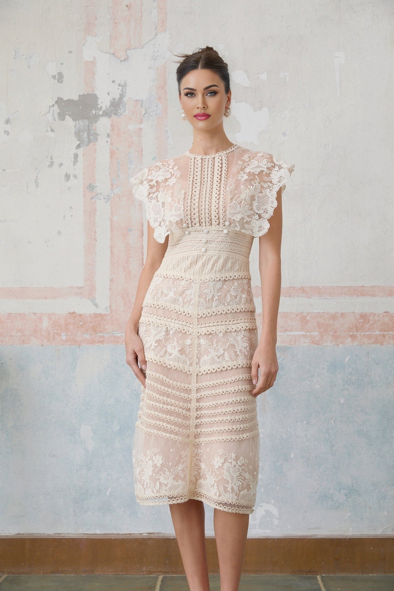 Woman wearing neutralcolored midi dress with floral embroidery and lace details standing in elegant pose