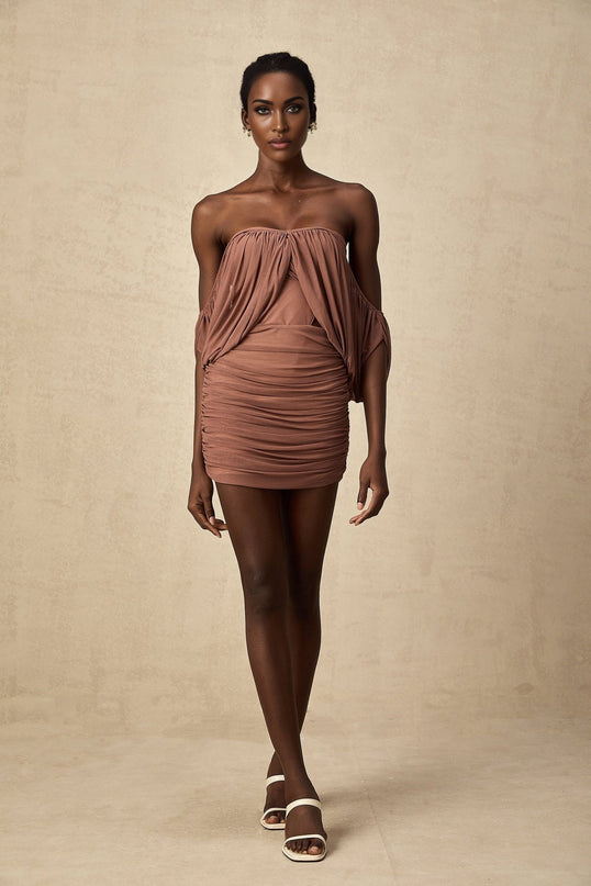 Woman wearing offshoulder bodysuit and matching skirt set in light color standing with hands on hips