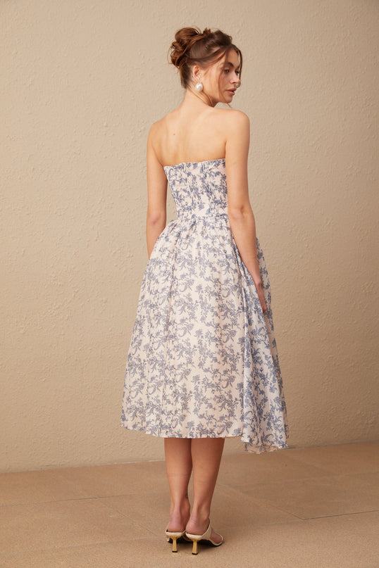 Woman wearing offshoulder floral print midi dress with ruffled neckline and fitted waist