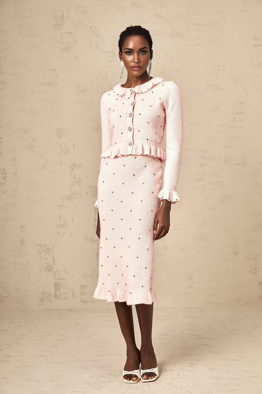 Woman wearing pink argyle patterned knitted cardigan and matching skirt set