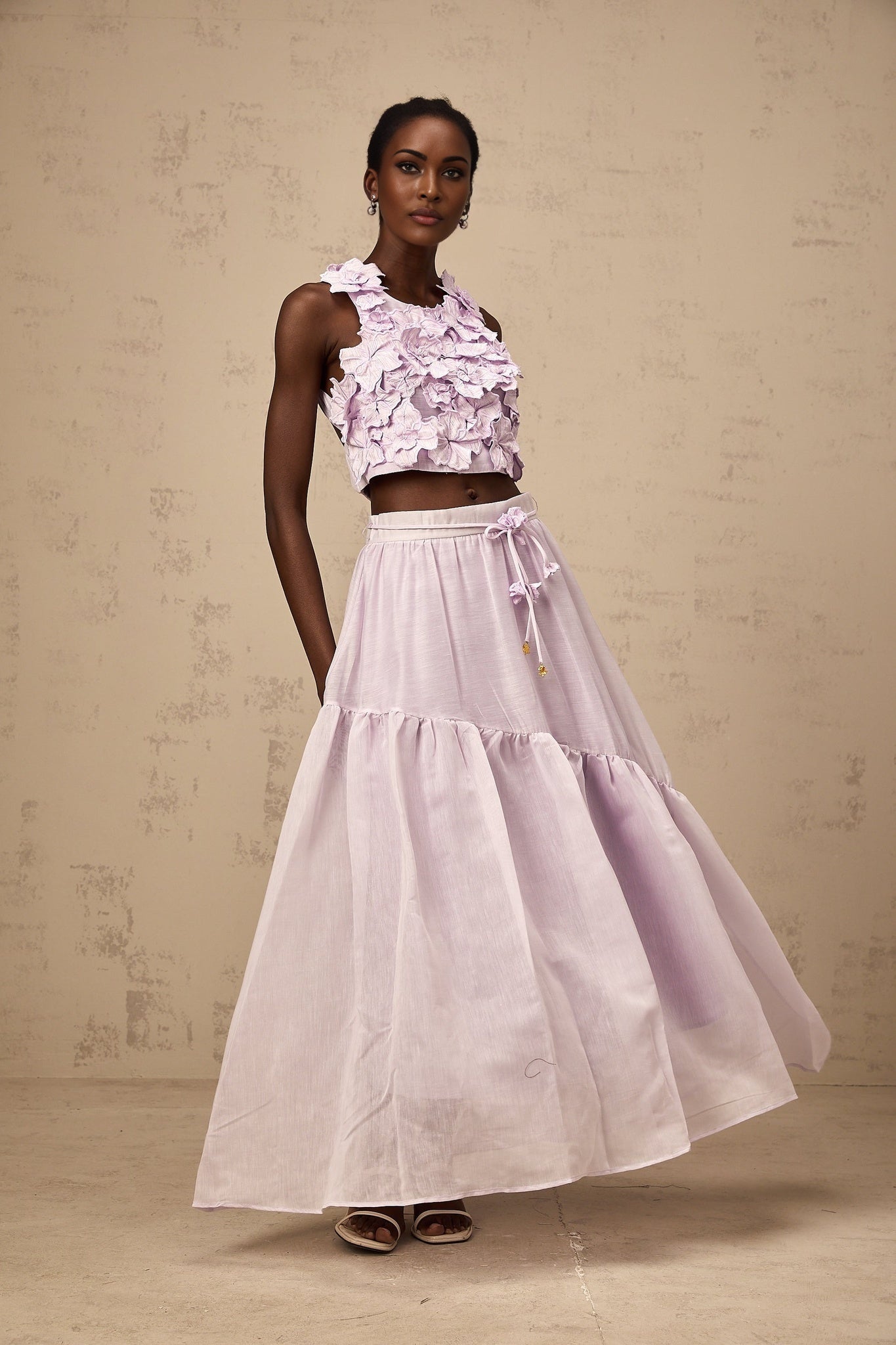 Woman wearing purple floral top and matching skirt with faux flower design