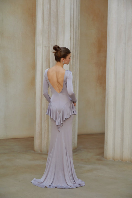 Woman wearing purple maxi dress with ruffle details and front slit standing in relaxed pose